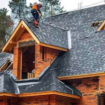 Roofer works on a shingle roof.